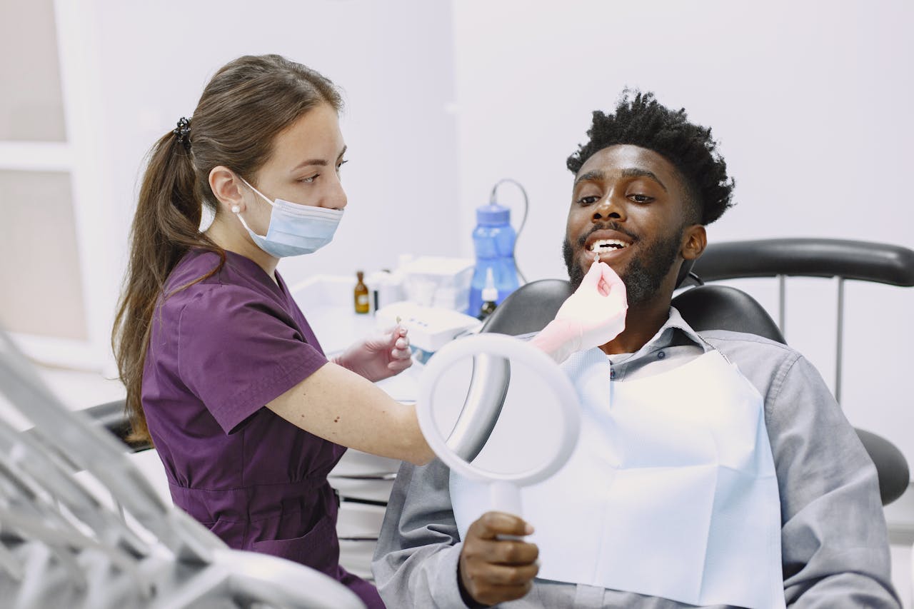 about-05 A dentist performs a check-up on a patient holding a mirror in a modern dental office.
