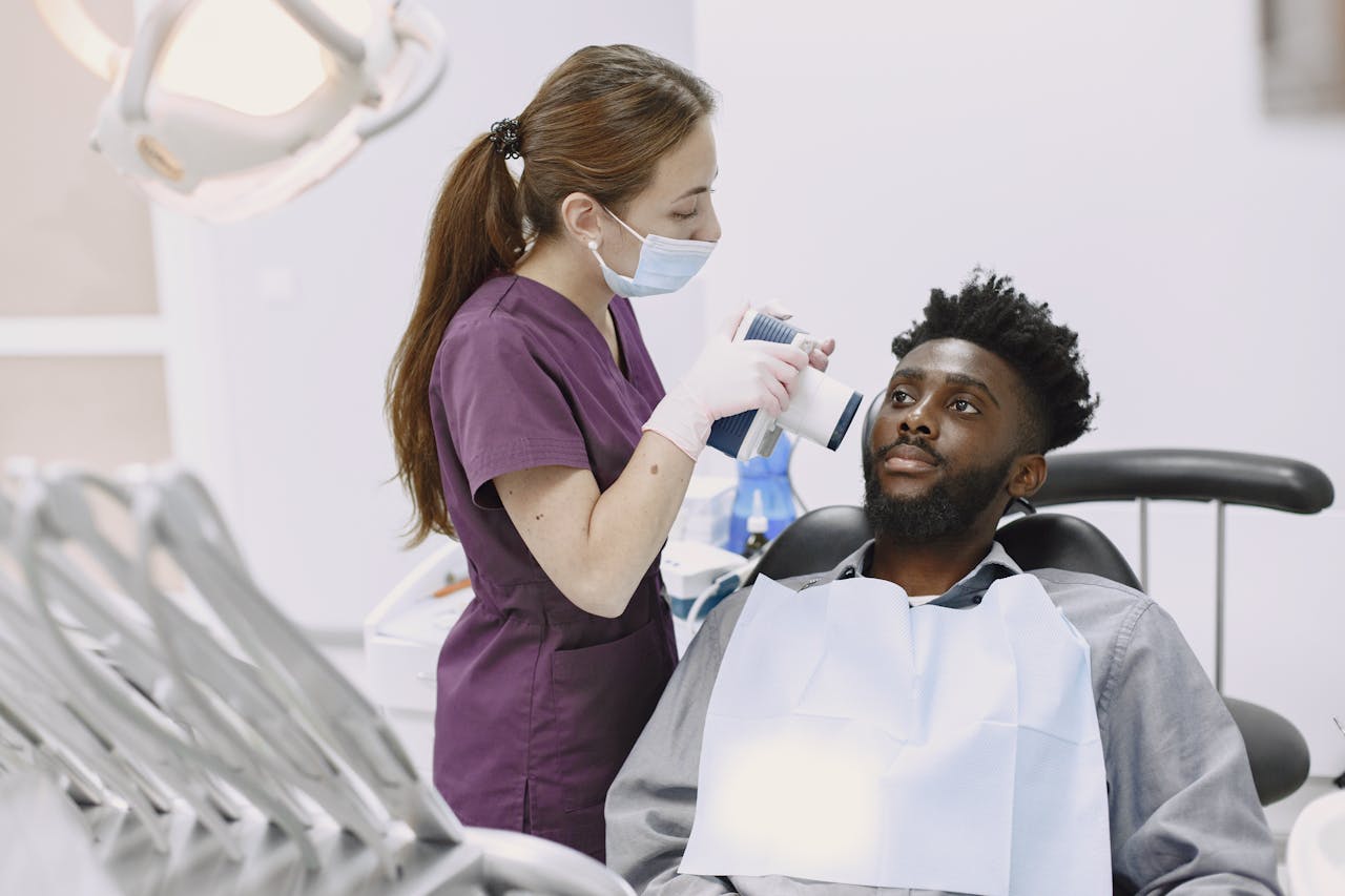 A dentist conducts a dental examination using modern equipment on a male patient.